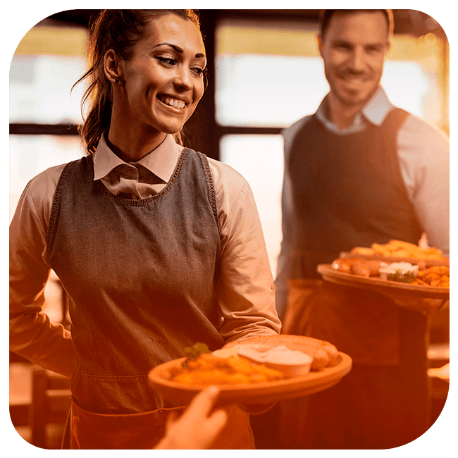 Dois garçons servindo comida em uma bandeja para alguns clientes.