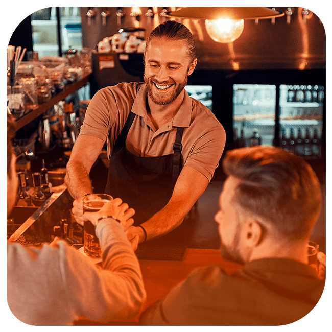 Barman servindo cerveja para dois clientes que estão do outro lado do balcão.